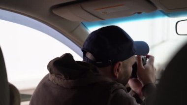 Özel dedektif ya da paparazziler arabanın içinde oturmuş refleks kamerayla fotoğraf çekiyorlar.