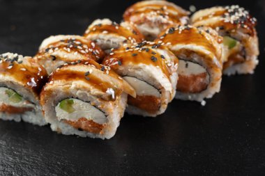 Somonlu suşi, füme yılan balığı, avokado, siyah arka planda Philadelphia peyniri. Suşi menüsü. Japon yemeği konsepti. Kapat.