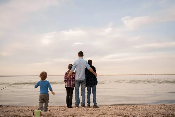 stock image silhouettes of a happy family of father and three children standing on the beach. vacation with children in nature concept