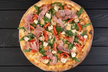 İtalyan mutfağı konsepti. Prosciutto, roka ve ahşap arka planda parmesanlı pizza. Boşluğu kopyala