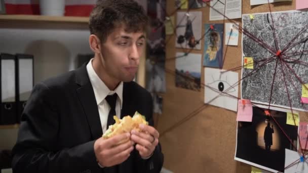 私家侦探在调查委员会和吃汉堡包 寻找解决方案 休息和零食脂肪汉堡包 不健康的食物概念 — 图库视频影像