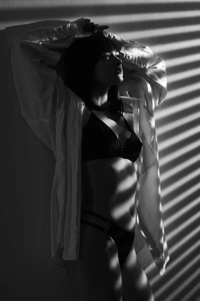 一个性感的黑发女人 身材非常苗条 站在墙边 穿着时髦的黑色内衣裤和白色男友衬衫 复制空间 — 图库照片