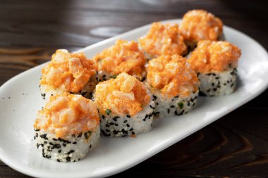 Japon suşi volkanı beyaz ve siyah susamlı. Tabakta servis ediliyor. Koyu ahşap arka plan. Boşluğu kopyala