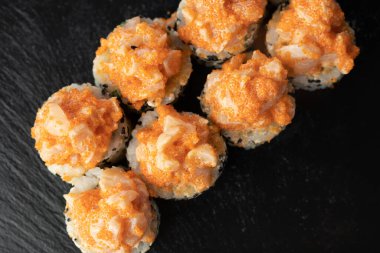 Volkanik suşi rulosu, Kaliforniya rulosu fırında deniz tarağı ve koyu ahşap arka planda yumurta, üst manzara. Boşluğu kopyala