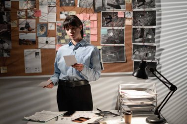 Dedektif ofiste çalışıyor ve katilin fotoğraflarına bakıyor. Dedektif cinayet detaylarını inceliyor. Boşluğu kopyala