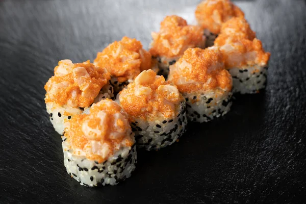 stock image Volcano sushi roll, California roll with baked scallops and smelt roe on dark wooden background, top view