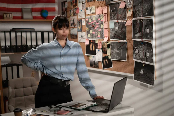 Female detective looking attentively at laptop computer. Copy space