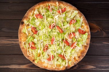 Beyaz soslu, tavuklu, parmesanlı, kiraz domatesli ve ahşap arka planda taze marullu pizza. Restoran pizzacısı menüsü kavramı