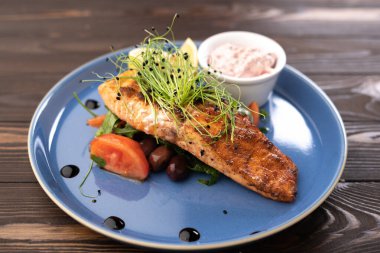 Ahşap masada pişmiş somon filetosu ve limon tabağı. Boşluğu kopyala