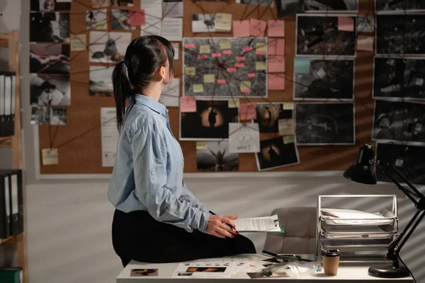 female detective looking at evidence board in her office. Copy space