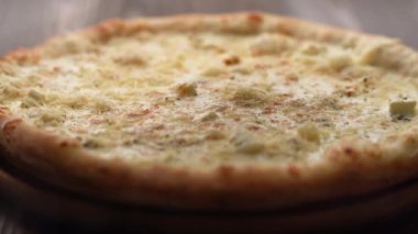 Tahtaya konmuş pizza Quattro formaggi. Kırsal ahşap bir zemine otlar dökülüyor. Kapat.