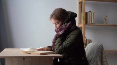 Soğuk salonda otururken battaniyeli ve kalın elbiseli kötü bir öğrenci. Sıcaktan muzdarip. Sağlıksız genç bir kadın evdeki dondurucu soğukla boğuşuyor. Isıtma kavramı yok.