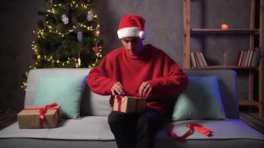 Noel Baba şapkalı Arap adam hediye paketleri getiriyor. Noel ağacı ışıklarındaki kanepeye paket paketi koyuyor. Tatil konseptinde nakliye, kurye hizmeti