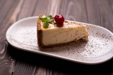 Lezzetli cheesecake, New York tarzı klasik peynirli kek, ahşap arka planda. Beyaz tabakta lezzetli bir pasta dilimi. Boşluğu kopyala