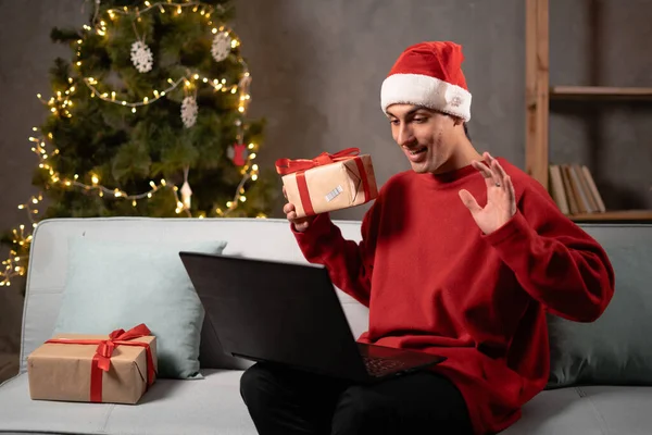 Uśmiechnięty Arabski Mężczyzna Noszący Czapkę Mikołaja Trzymający Pudełko Świąteczne Machający — Zdjęcie stockowe