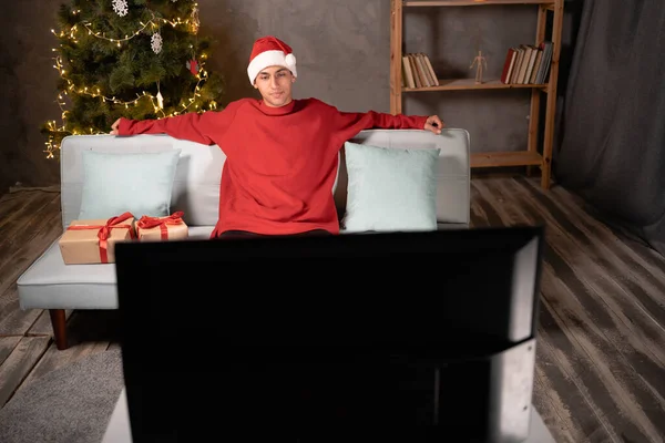 クリスマス 新年とクリスマスの前夜を祝うために飾られた部屋で 自宅でテレビを見ている若い男 スペースのコピー — ストック写真