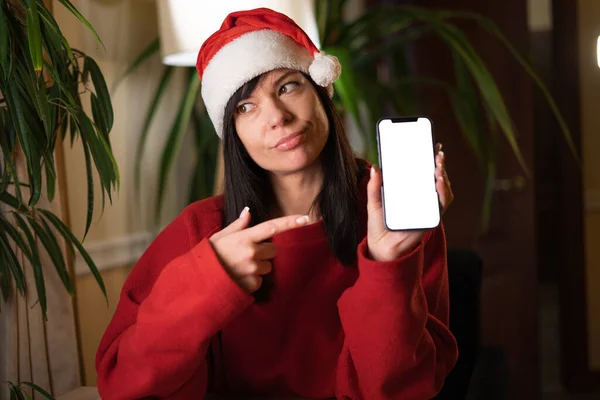 Młoda Mikołajowa Kobieta Wskazując Palcem Mobilny Smartfon Pusty Ekran Wigilię — Zdjęcie stockowe