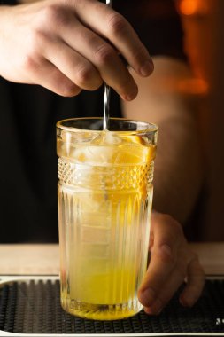 Profesyonel barmen bar tezgahında kaşıkla soğuk kokteyl karıştırır. Boşluğu kopyala