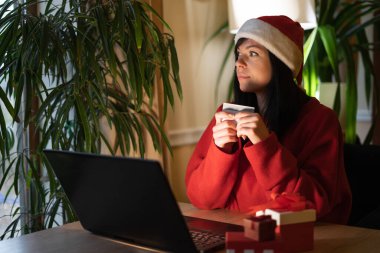 Noel Baba şapkalı kadın online alışveriş için dizüstü bilgisayar kullanıyor, Noel 'i kutlayan müşteri. Kış indirimi, Noel alışverişi, kredi kartıyla hediyeler. Boşluğu kopyala