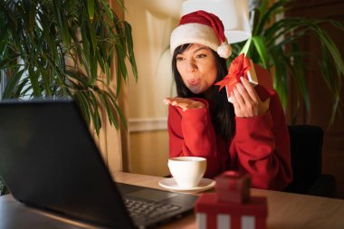 Mutlu hippi kadın, Noel arifesinde evinde dizüstü bilgisayarla kocasına hava öpücüğü verirken. Boşluğu kopyala