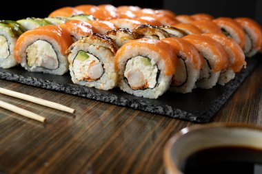 Suşi seti, somon, karides ve filadelfiya salatası ahşap masada servis edilir. Japon Gıda Konsepti