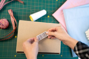 Başlangıçta küçük işletme KOBİ sahibi kadın girişimciler ürün taşıma sipariş kutusu paketliyor, barkodlu teslimat paketini etiketliyorlar. Çevrimiçi satış, e-ticaret kavramı