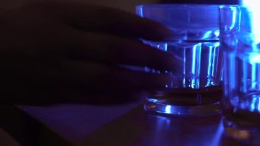 Barmen boş bardakları neon ışıklarıyla tezgaha koyuyor.