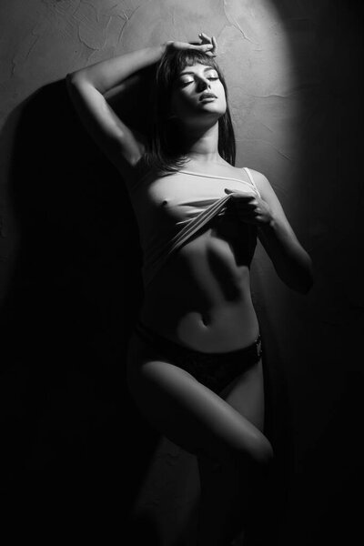 Sensual sexy young aroused woman with closed eyes posing on black background, monochrome. Copy space
