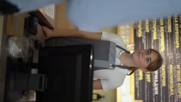 在咖啡店柜台上微笑的女服务员 女店员 男客户通过自动售货机在咖啡店用电话支付非接触式移动支付 垂直录像 — 图库视频影像
