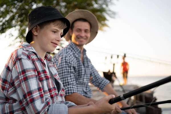 boy teen and his father fishing together from a pier. Copy space