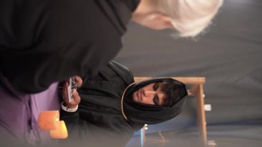 Tarot okuyucusu bayan müşteri için tarot kartları seçiyor. Tarot kartları yanan mumların yakınındaki masanın üzerine dönük. Mum ışığı. Tarot okuyucu veya falcı okuma ve tahmin konsepti.