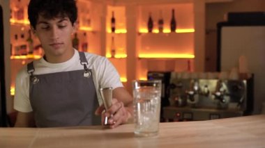 Barmen bardaki bir bardağa alkollü içki dolduruyor.