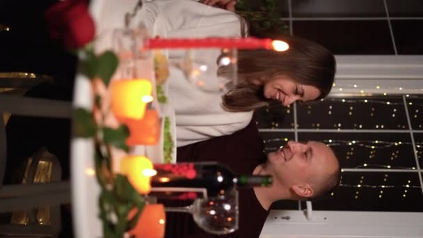恋爱中的快乐夫妻在家里或餐馆庆祝情人节 他们与蜡烛约会 坐在浪漫的餐桌旁 2月14日庆祝情人节 垂直录像 — 图库视频影像