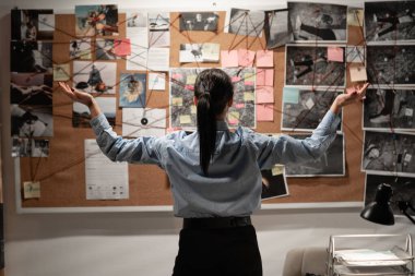 Dedektif ofis meditasyonunda kanıt panosuna bakıyor. Elleri havada, geriye doğru bakıyor. Boşluğu kopyala