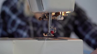 Moda atölyesinde çalışırken dikiş makinesinde dikiş diken bir kadın.