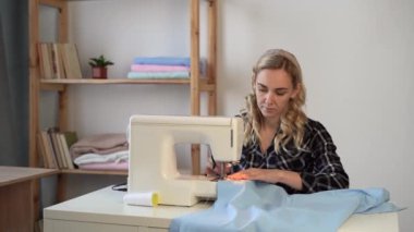 Kadın terzi ya da terzi dikiş makinesine dikiş diker. Terzi, iş yerinde giysi yapıyor. Küçük bir iş konsepti olarak hobi dikiş dikmek