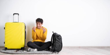 Bana nakit ver. Bavullu genç Arap bir gezgin sinsice gülümsüyor ve para jesti yapıyor, ödeme ve harçlık istiyor. Stüdyo çekimi beyaz arka planda izole edilmiş. Boşluğu kopyala