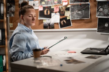 Ofisinde çalışırken ipuçlarını dikkatlice değerlendiren zeki bir dedektif. Boşluğu kopyala