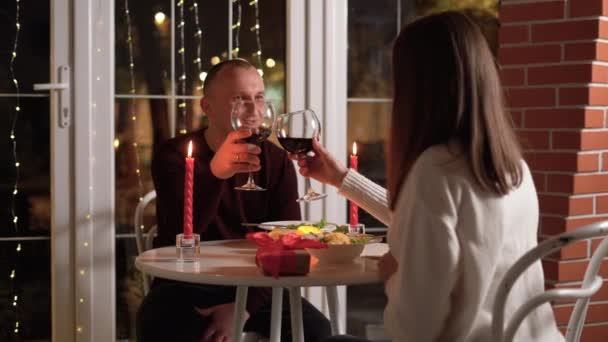 一对年轻貌美的夫妇在一家豪华餐厅里举杯红葡萄酒 在爱情中祝酒庆祝情人节 浪漫的烛光晚餐 — 图库视频影像