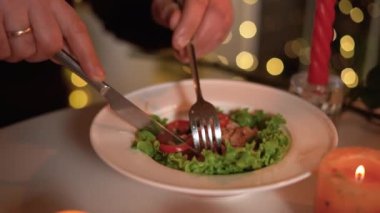 Masada romantik, lezzetli bir akşam yemeği, yakın çekim erkek elleri et salatası yiyor.
