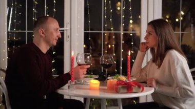 Mutlu çift mum ışığında romantik bir akşam yemeği yiyor. Sevgililer Günü konseptinde randevu