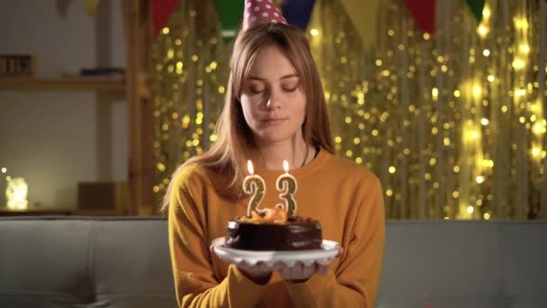 23岁生日一个年轻的女人在生日蛋糕上吹点23点的蜡烛 女孩抱着美味的蛋糕许愿 — 图库视频影像