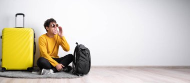 Sarı bavulla seyahat etmeye hazır genç bir Arap bağırarak ve avuç içini açık tutarak. Pankart