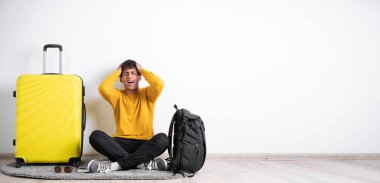 Baş ağrısı olan hasta bir gezgin izole edilmiş beyaz arka planda bavuluyla otururken migren ve sağlık sorunları yaşıyor. Pankart