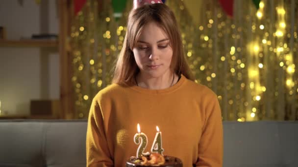24岁生日一个年轻的女人在生日蛋糕上吹着二十四支蜡烛 女孩抱着美味的蛋糕许愿 — 图库视频影像