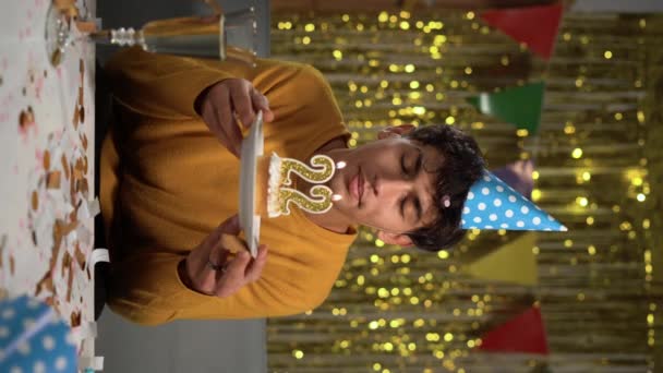 ケーキの中で22歳の誕生日を祝う誕生日キャンドル 若い男が願い事をしてろうそくを吹き消すと 家で誕生日を祝う 垂直ビデオ — ストック動画