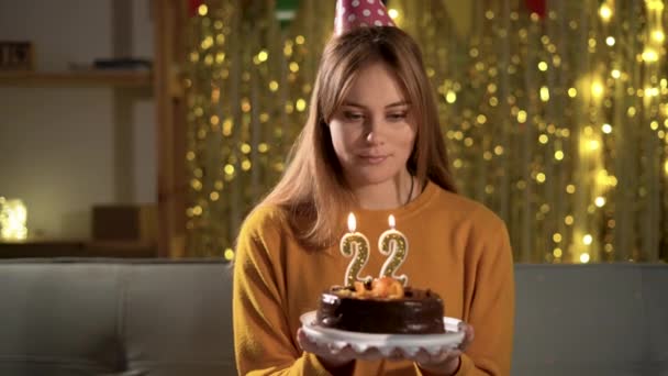 22歳の誕生日 誕生日ケーキに20個のろうそくを吹いている若い女性 おいしいケーキを持ちながら願い事をする女の子 — ストック動画