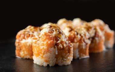 Peynirli suşi rulosunu kapat. Deniz ürünleri ve yengeçli fırında suşi, siyah arka planda krem peynir. Boşluğu kopyala