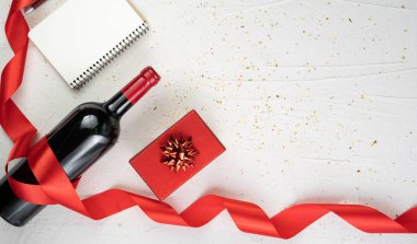 Sevgililer günü dekoru, hediye kutusu, şarap şişesi ve izole edilmiş beyaz arka planda kırmızı ipek kıvrımlı kurdele. Pankart