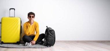 Bagajı olan genç bir Arap turist sessizlik ve sessizlik istiyor, parmağıyla ağzının önünde işaret ediyor, 